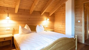 Et soveværelse i en træhytte med en seng, to sengeborde og vægmonterede lamper.
