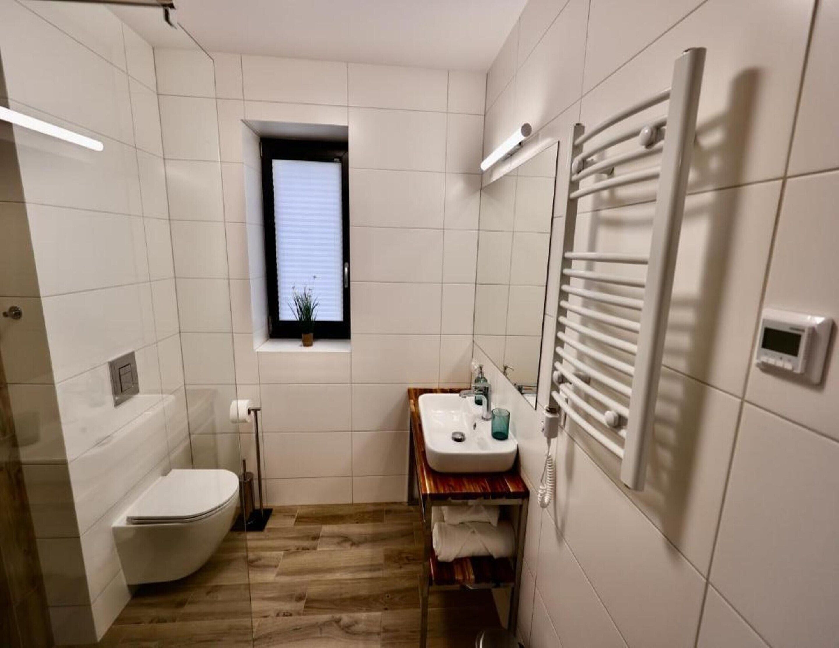 Ein kleines Badezimmer mit Toilette, Waschbecken und Fenster.