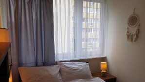 A bedroom with a bed, a bedside lamp, a window with curtains, and a wall decoration. - Condo in Swinoujscie Near Baltic Sea Beach (Swinoujscie)
