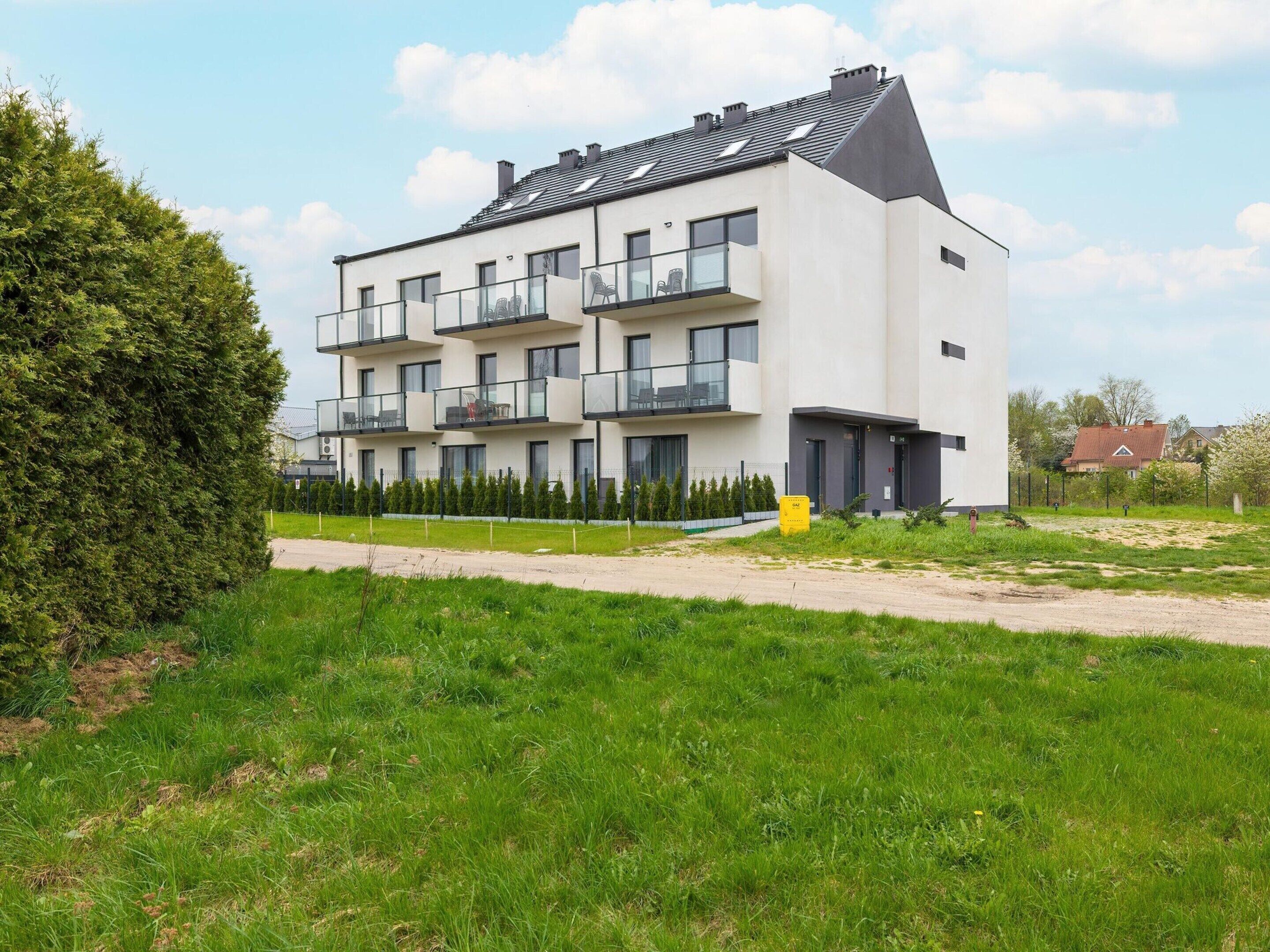 Ein modernes Mehrfamilienhaus mit Balkonen, einer flachen Dachkonstruktion und einem gepflegten Rasen davor.