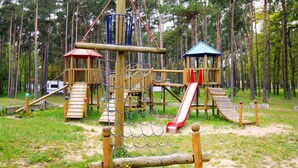 Un'area giochi con scivolo, rete da arrampicata e strutture in legno.