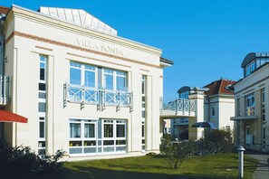 Un edificio con la scritta "Villa Sonja" sulla facciata, caratterizzato da ampie finestre e un balcone con ringhiera intagliata.