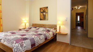 Un dormitorio con una cama de madera, colcha, dos lámparas de noche y un cuadro de una jirafa en la pared.