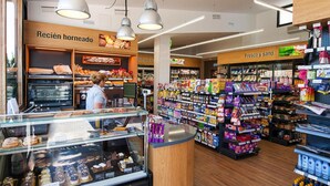 Un rayon boulangerie avec une vitrine remplie de pâtisseries et un comptoir où se trouve la caisse.
