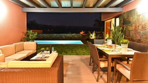 Une terrasse extérieure avec une piscine, des sièges et un espace repas.
