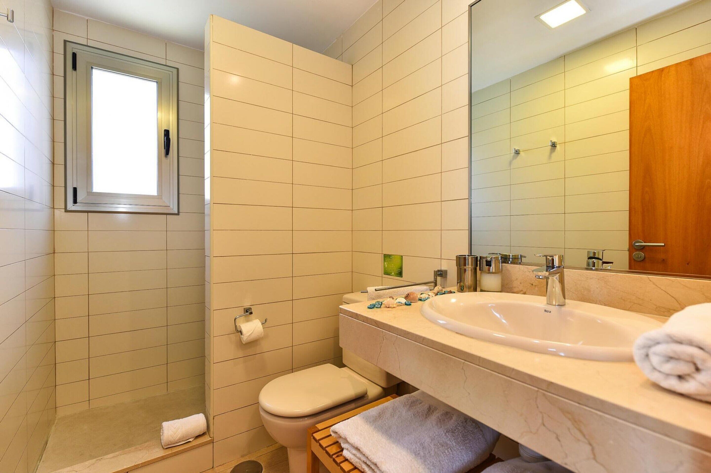 Ein Badezimmer mit Dusche, Toilette, Waschbecken und einem großen Spiegel.