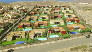 Un quartier résidentiel où les maisons sont alignées en rangées, avec de petits jardins devant et une route au premier plan.
