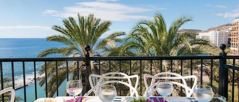 Une table dressée pour deux personnes, avec vue sur la mer et les palmiers.