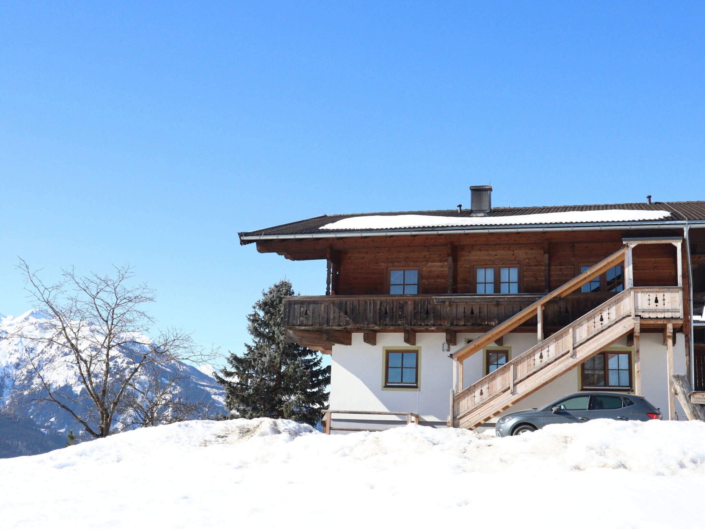 Een houten chalet met een balkon en een auto ervoor geparkeerd.