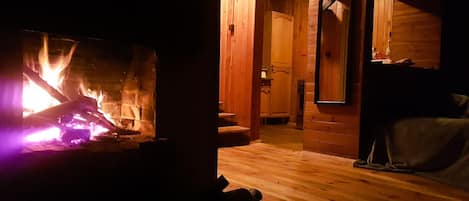 A cozy room with a fireplace, wooden walls, and a mirror.
