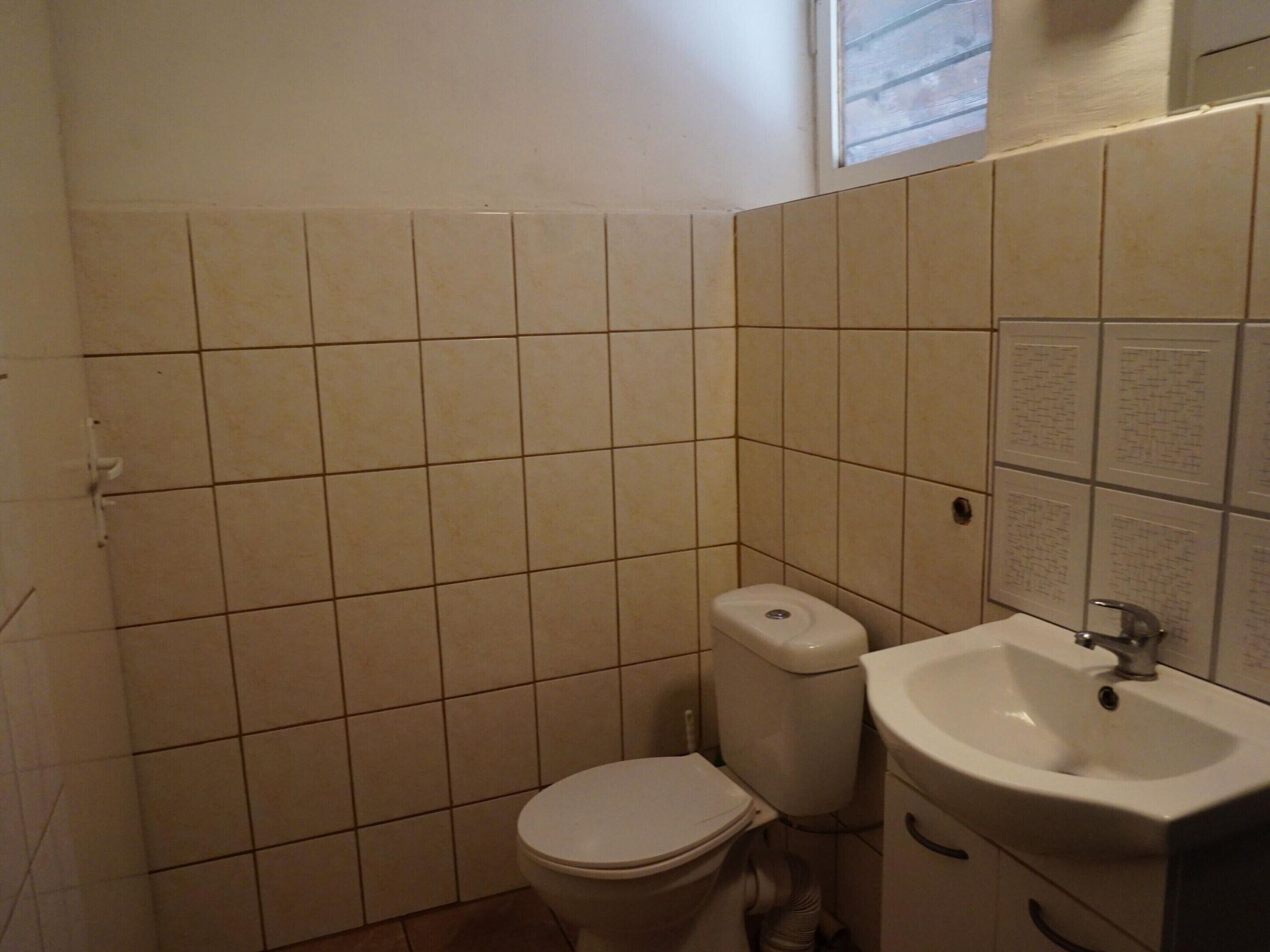 A small, tiled bathroom with a toilet and a sink.