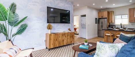 Relax in this stylish living space with a flat-screen TV, comfortable sofa, and a potted plant.