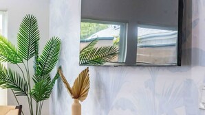 Un comptoir d’accueil moderne, doté d’un revêtement en bois, flanqué de grandes plantes vertes et d’un vase décoratif.
