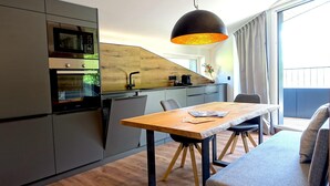 A modern kitchen with built-in appliances, a wooden accent wall, and a dining area with a table and chairs.