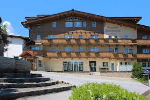 Un hôtel à plusieurs étages, doté de balcons, d’une façade en pierre et d’une enseigne indiquant qu’il s’agit des appartements Brunner.