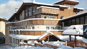 Un immeuble à plusieurs étages, dont le toit et les balcons sont recouverts de neige.