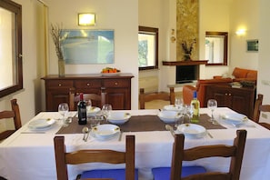 A dining room with a table set for four, a fireplace, and a painting on the wall. - Villa on Costa Rei Near Sandy Beach (Muravera)
