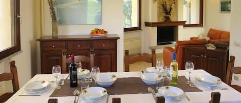 Un coin repas avec une table dressée pour quatre personnes, une cheminée et un tableau accroché au mur.