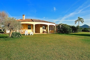 A house with a patio, a lawn, and a mountain in the background. - Villa on Costa Rei Near Sandy Beach (Muravera)