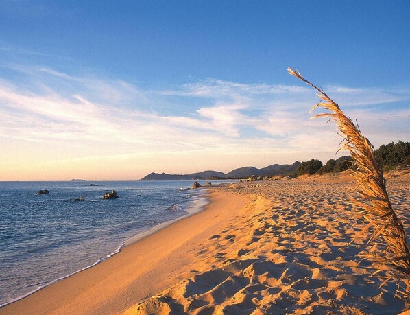 A beach with clear skies, calm water, and distant mountains. - Villa on Costa Rei Near Sandy Beach (Muravera)