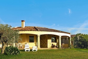 A house with a curved roof, a chimney, and a patio with outdoor furniture. - Villa on Costa Rei Near Sandy Beach (Muravera)