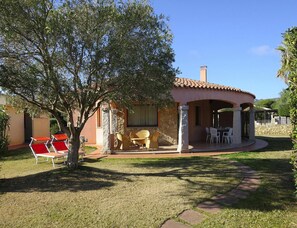 A house with a patio, outdoor seating, and a tree. - Villa on Costa Rei Near Sandy Beach (Muravera)
