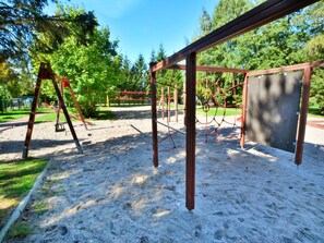 A playground with swings and a climbing net structure. - Holiday Home in Ustronie Morskie Near Beach (Ustronie Morskie)