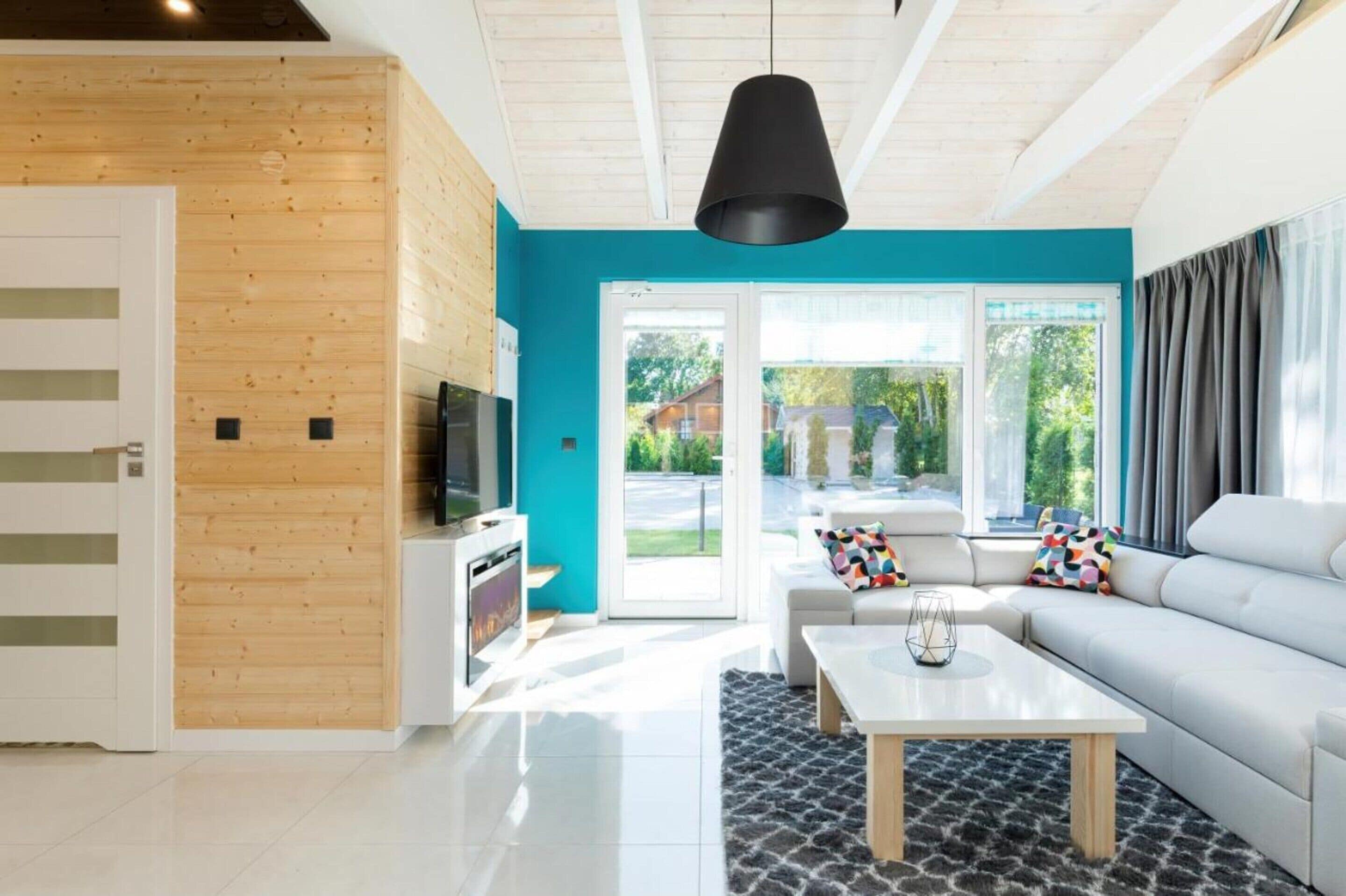 A modern living room with a wooden accent wall, a large window, and a white sofa.