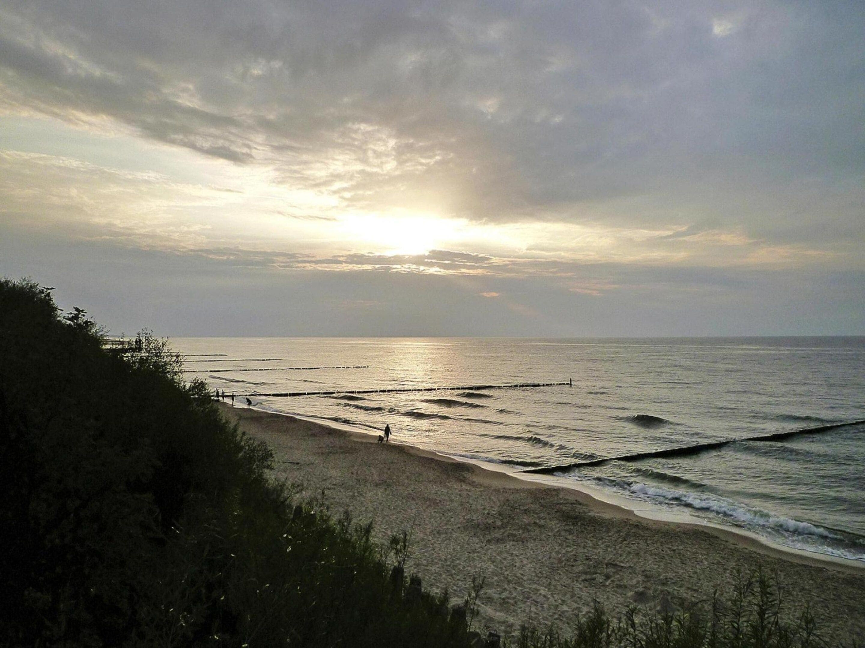 A beach with waves and a sunset in the background.
