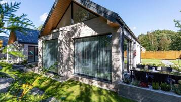 A modern house with a sloped roof, large windows, and a well-maintained garden.