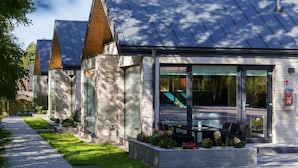 A modern building with large windows and a patio area with outdoor seating.