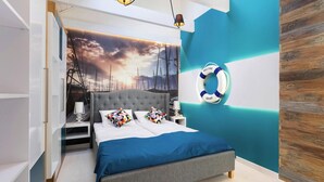 A modern bedroom with a large bed, a "Welcome" sign, and a nautical-themed wall mural.