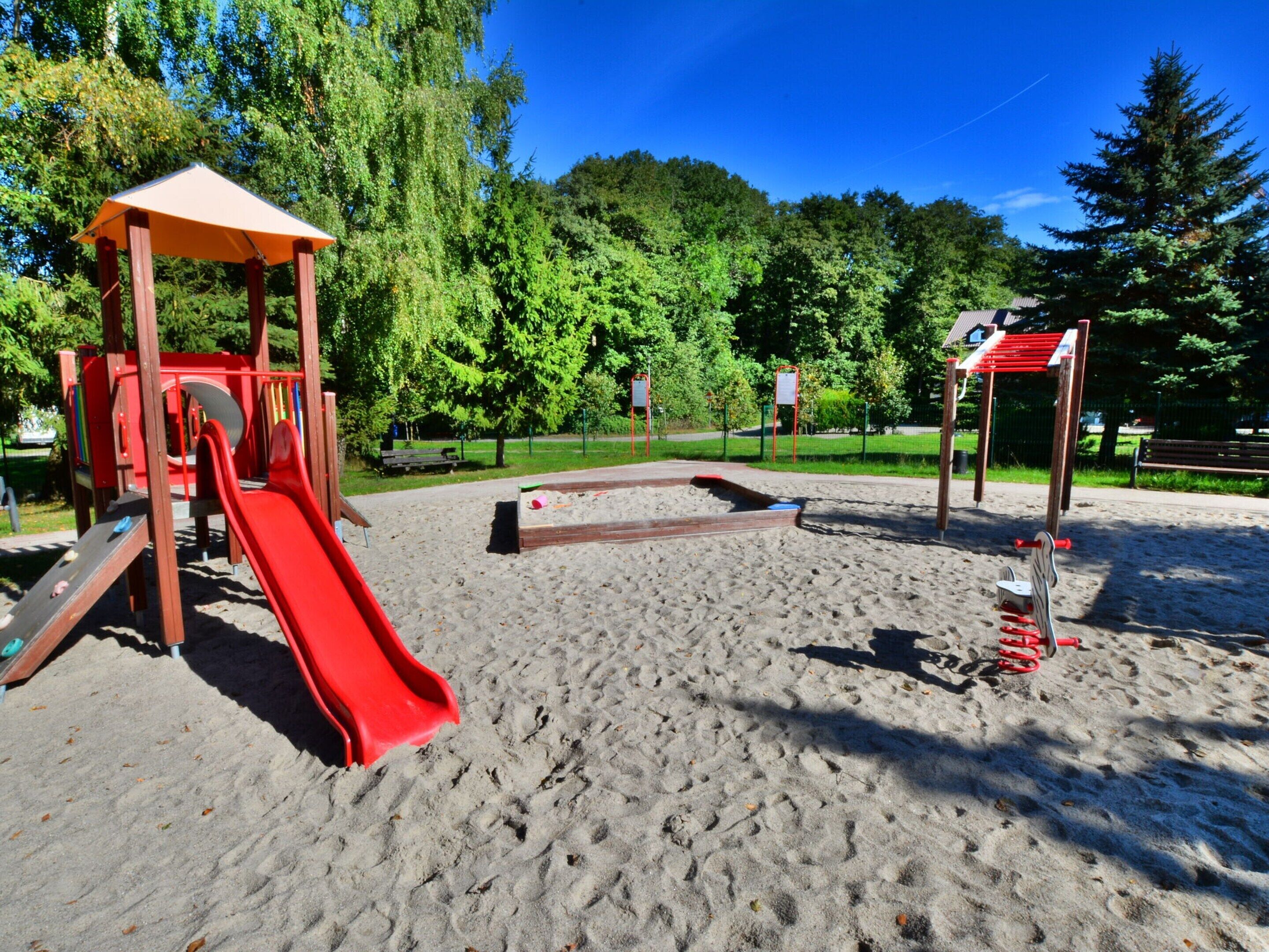 Ein Spielplatz mit Rutsche, Sandkasten und Klettergeräten.