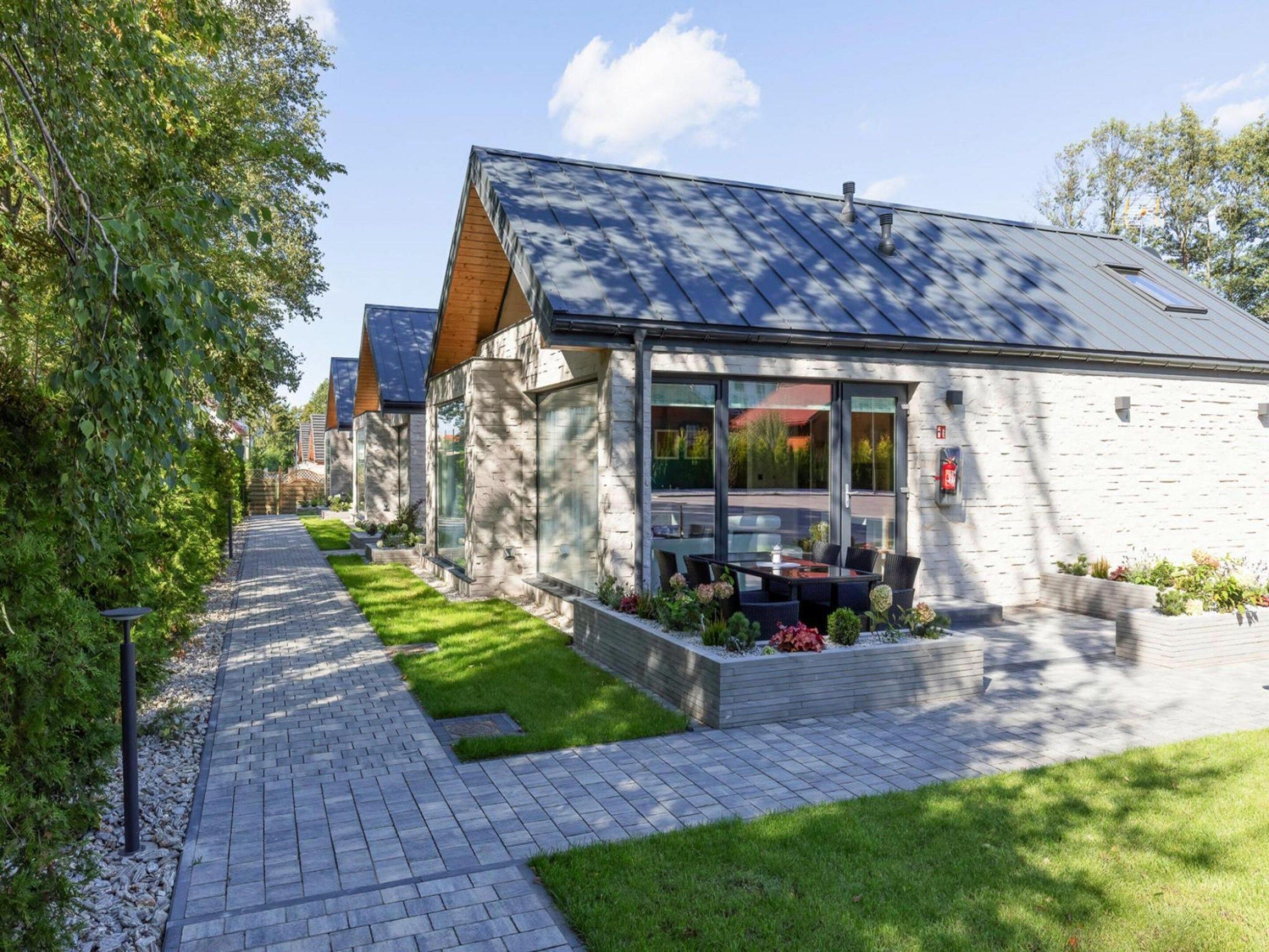 Ein modernes Gebäude mit einem gepflasterten Weg, einer Grünfläche und blauem Himmel.