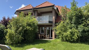 A two-story house with a balcony, surrounded by greenery and a lawn. - Ferienwohnung, Fedderwardersiel (Butjadingen)