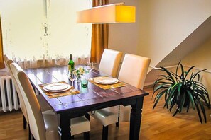 Une table à manger dressée avec des assiettes, des verres et une bouteille, entourée de chaises.