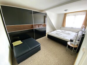Une chambre à coucher de taille réduite, comprenant un lit, un petit coin salon et une armoire.