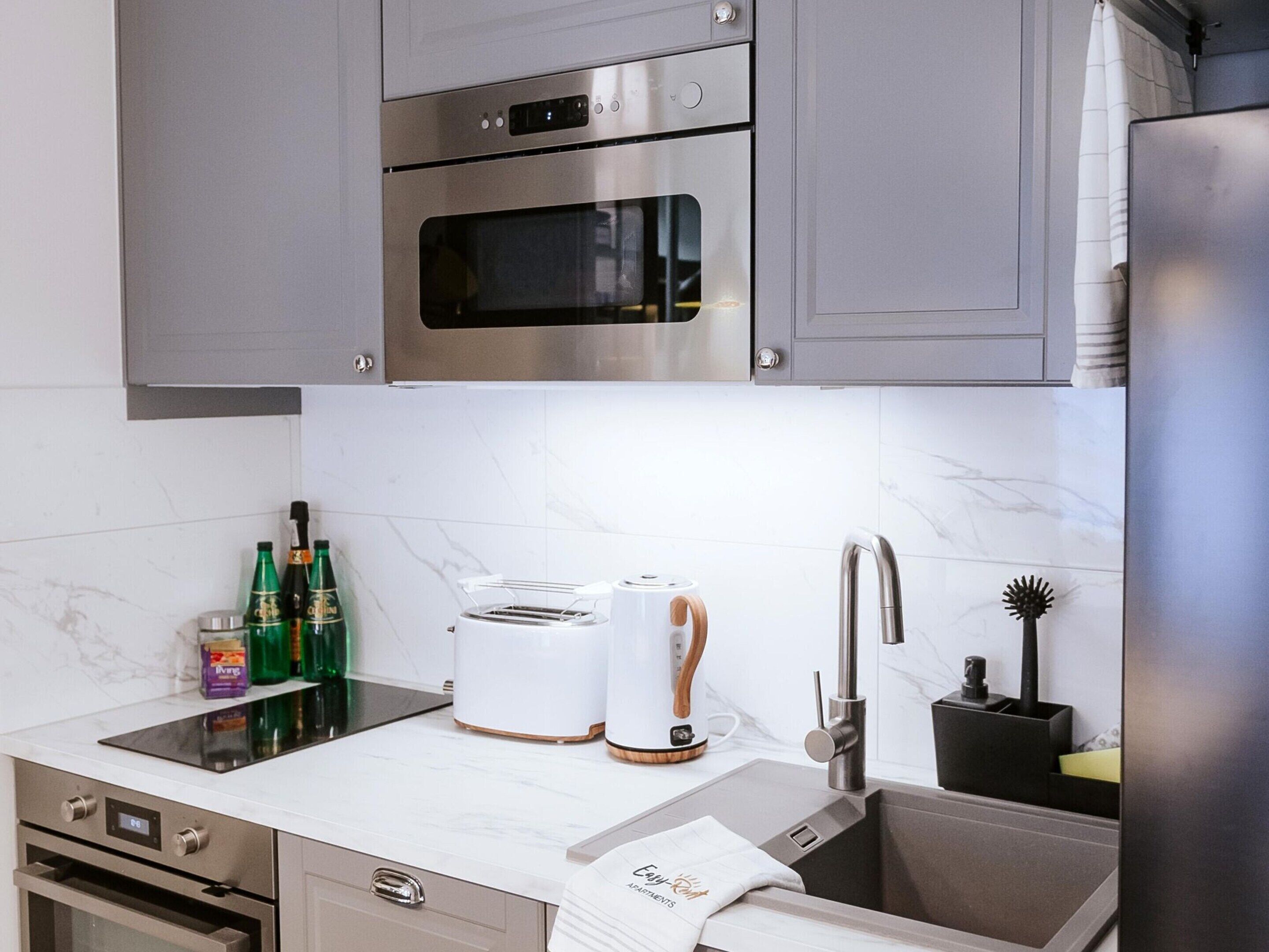 Eine moderne Küche mit Edelstahlgeräten, einer Marmor-Spritzschutzleiste und einem eingebauten Backofen.