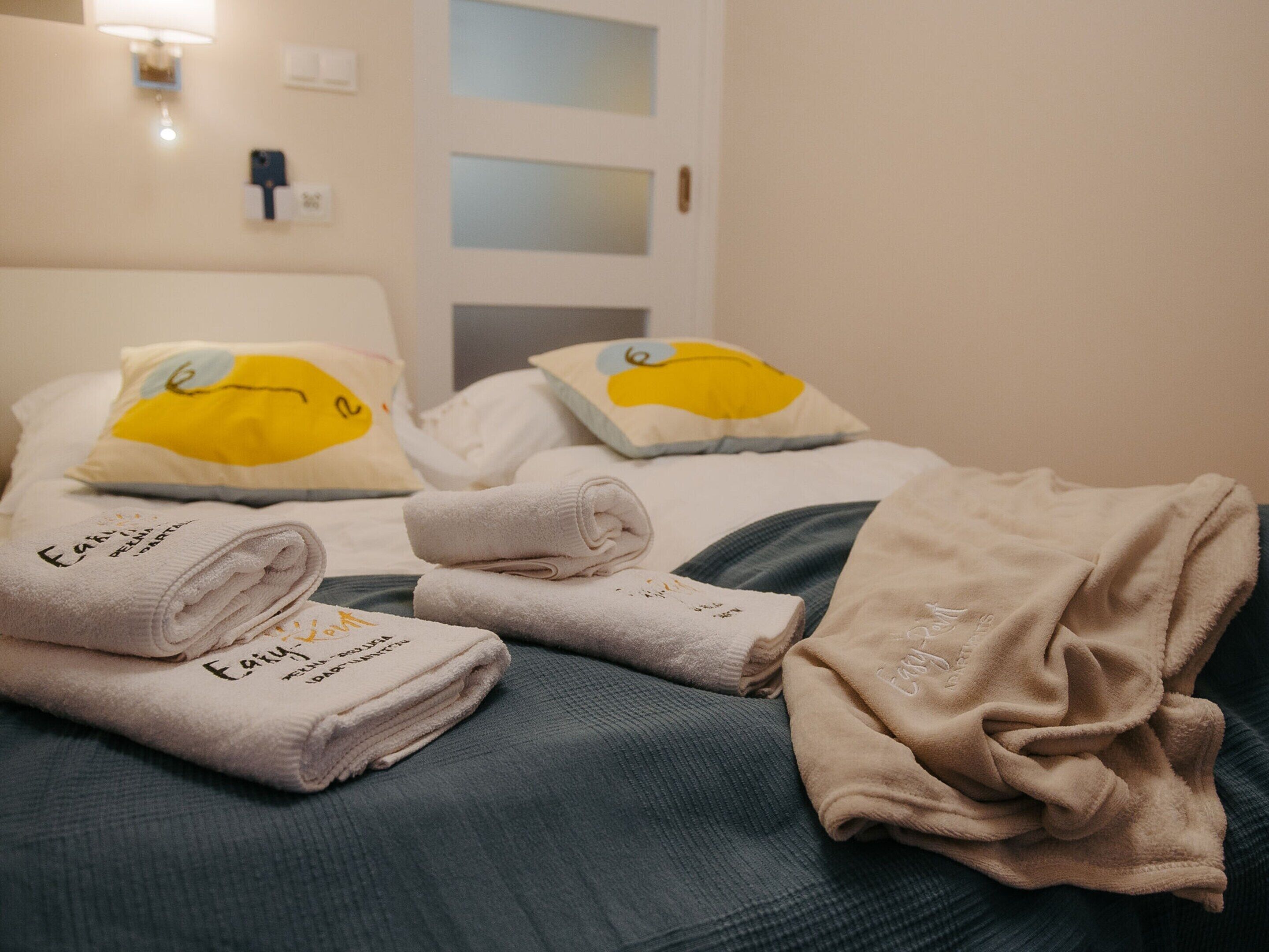 Una habitación de hotel con una cama, almohadas con caras de dibujos animados y toallas dobladas con cuidado.