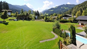 A residential area with houses, a swimming pool, and a large green field. - Apartment House Isegrim, Altenmarkt (Altenmarkt im Pongau)