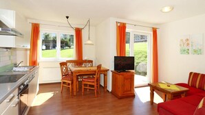 A modern kitchen with a dining area, a TV, and a red sofa. - Apartment House Isegrim, Altenmarkt (Altenmarkt im Pongau)