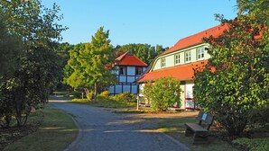 Un chemin de campagne menant à une maison traditionnelle avec un toit rouge et des murs blancs.