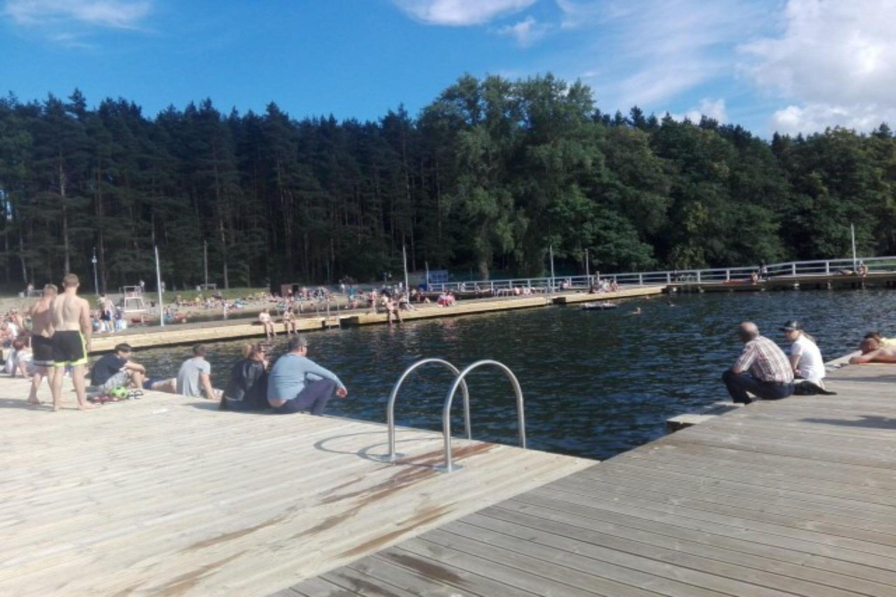 Een houten steiger die zich uitstrekt over het water, met mensen die er op zitten en staan.