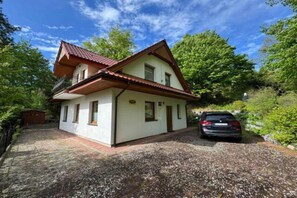 A two-story house with a sloped roof, a gravel driveway, and a parked car. - Holiday Home in Kretowiny Near Lake (Morag)