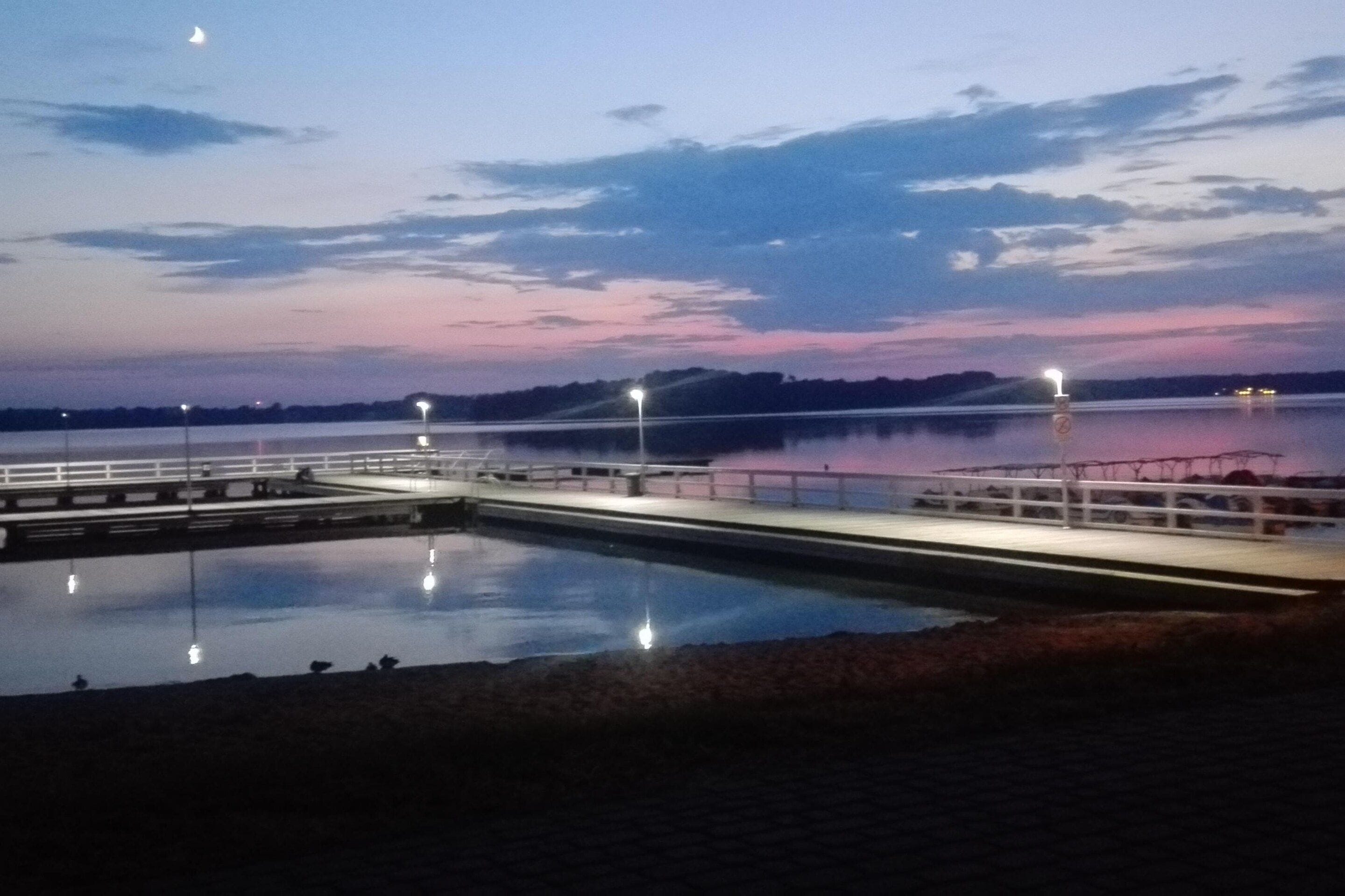 Una orilla tranquila con un muelle y un puente.