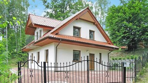 A two-story house with a red-tiled roof, white walls, and a black wrought iron gate. - Holiday Home in Kretowiny Near Lake (Morag)
