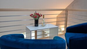 A balcony with a white table, a vase with red flowers, a bottle, and two blue chairs. - Apartment in Rewal Near Baltic Sea Beach (Rewal)