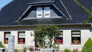 A two-story house with a dark roof, white walls, and a small garden with potted plants. - Ferienhauser am Teich, Zinnowitz (Zinnowitz)
