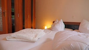A hotel room with a bed, a wardrobe, and a nightstand with a lamp. - Ferienhauser am Teich, Zinnowitz (Zinnowitz)