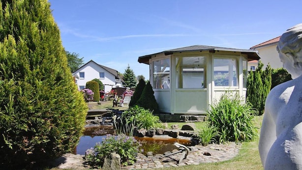 A garden with a pond, a gazebo, and a statue. - Ferienhauser am Teich, Zinnowitz (Zinnowitz)